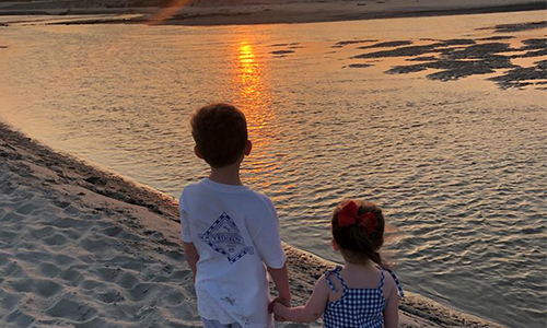 kids holding hands sunrise on beach
