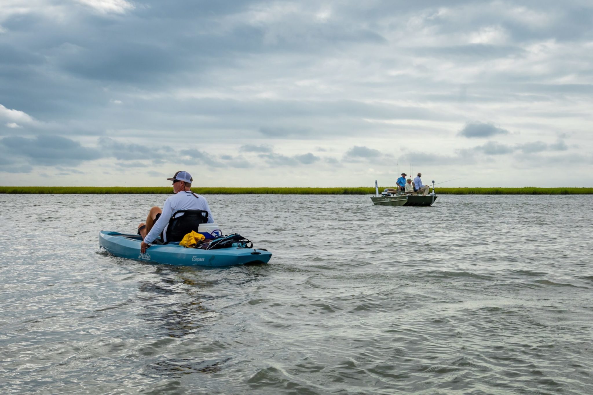 Guys fishing on the river One in a kayak and the others in a boat