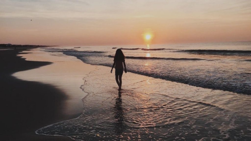 Girl walking on the beach during a sunrise