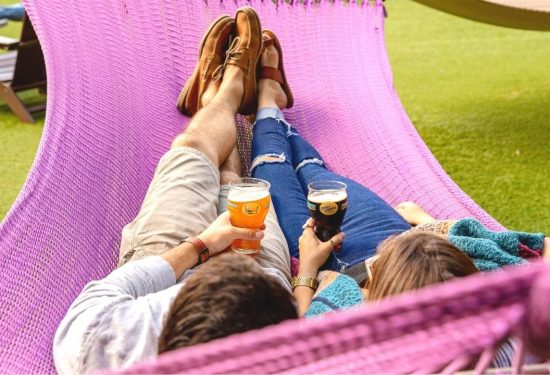 Couple sitting on hammock with beer