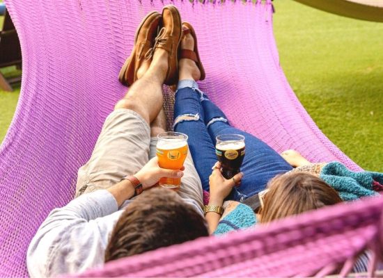Couple sitting on hammock with beer